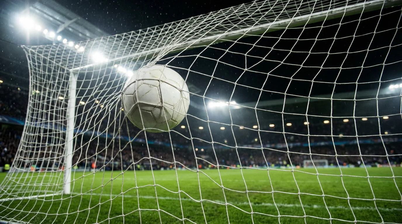 Pallone da calcio che entra in rete durante una partita serale sotto i riflettori